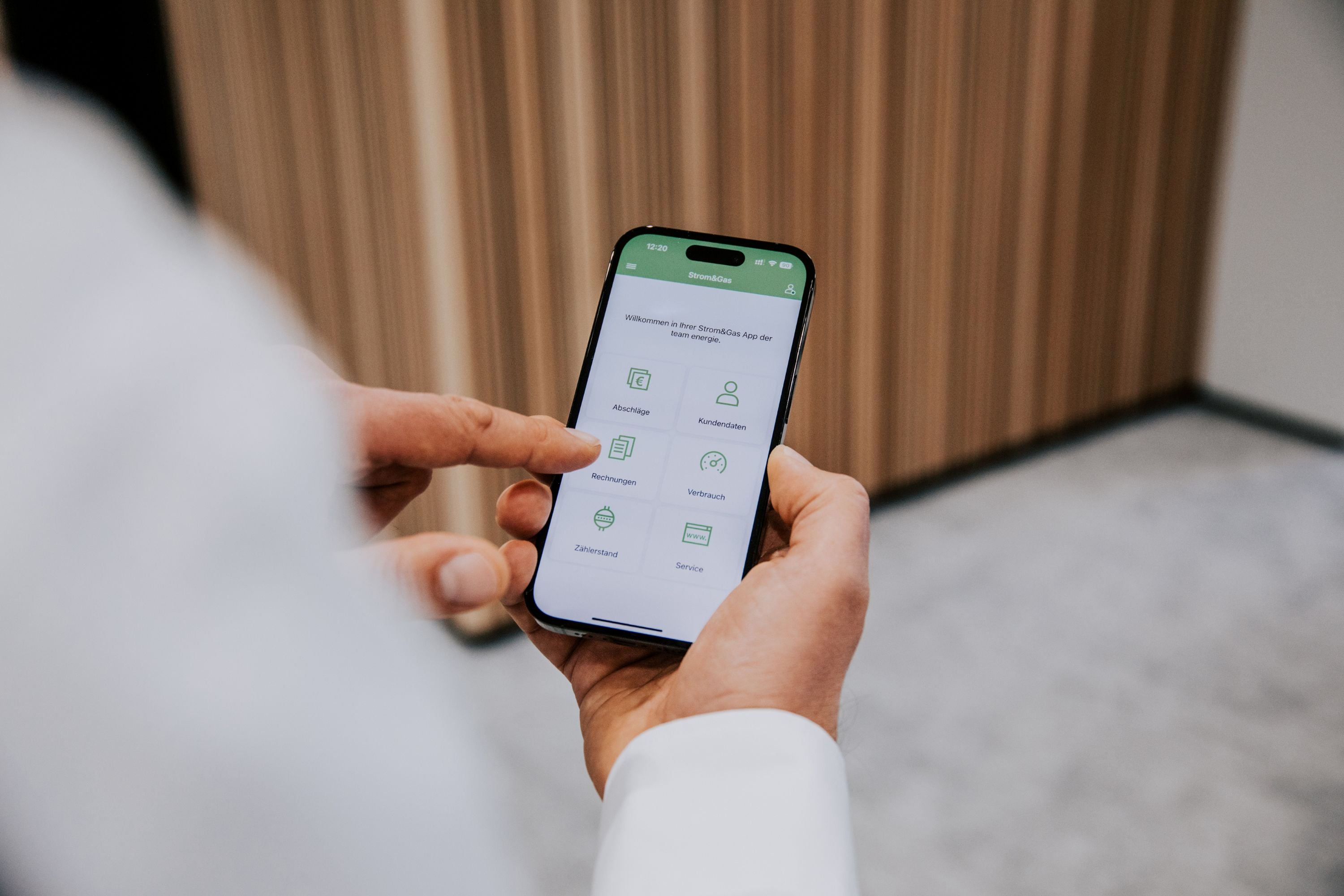 Someone holding a smartphone and navigating a Team-branded app.